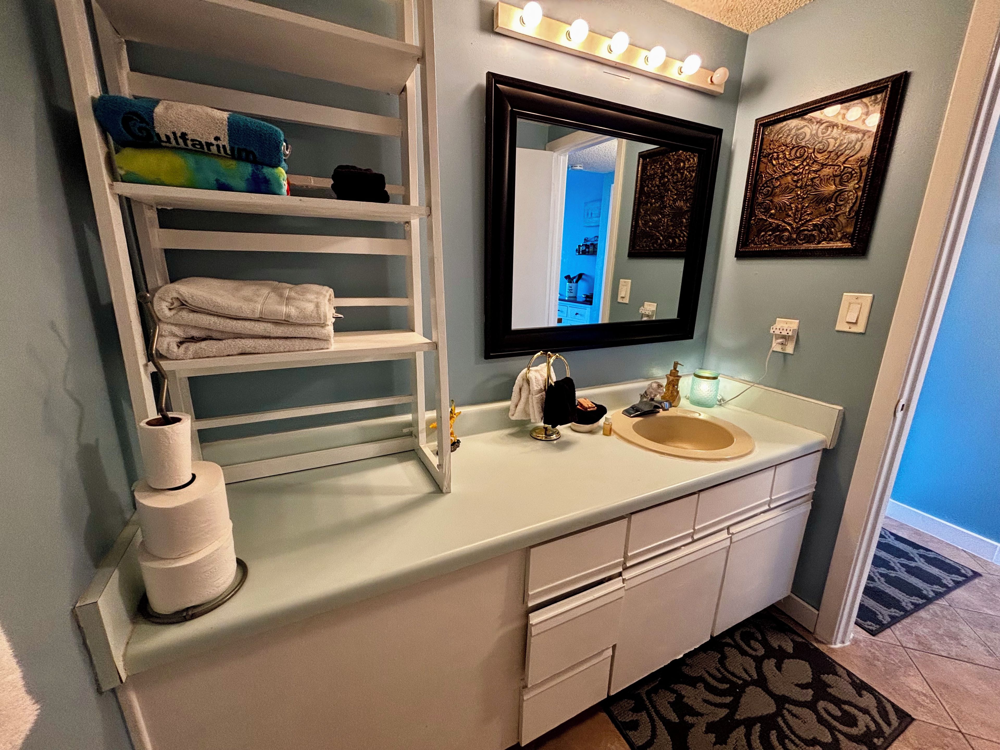 A bathroom with a vanity, a towel rack, a mirror, and a sink.