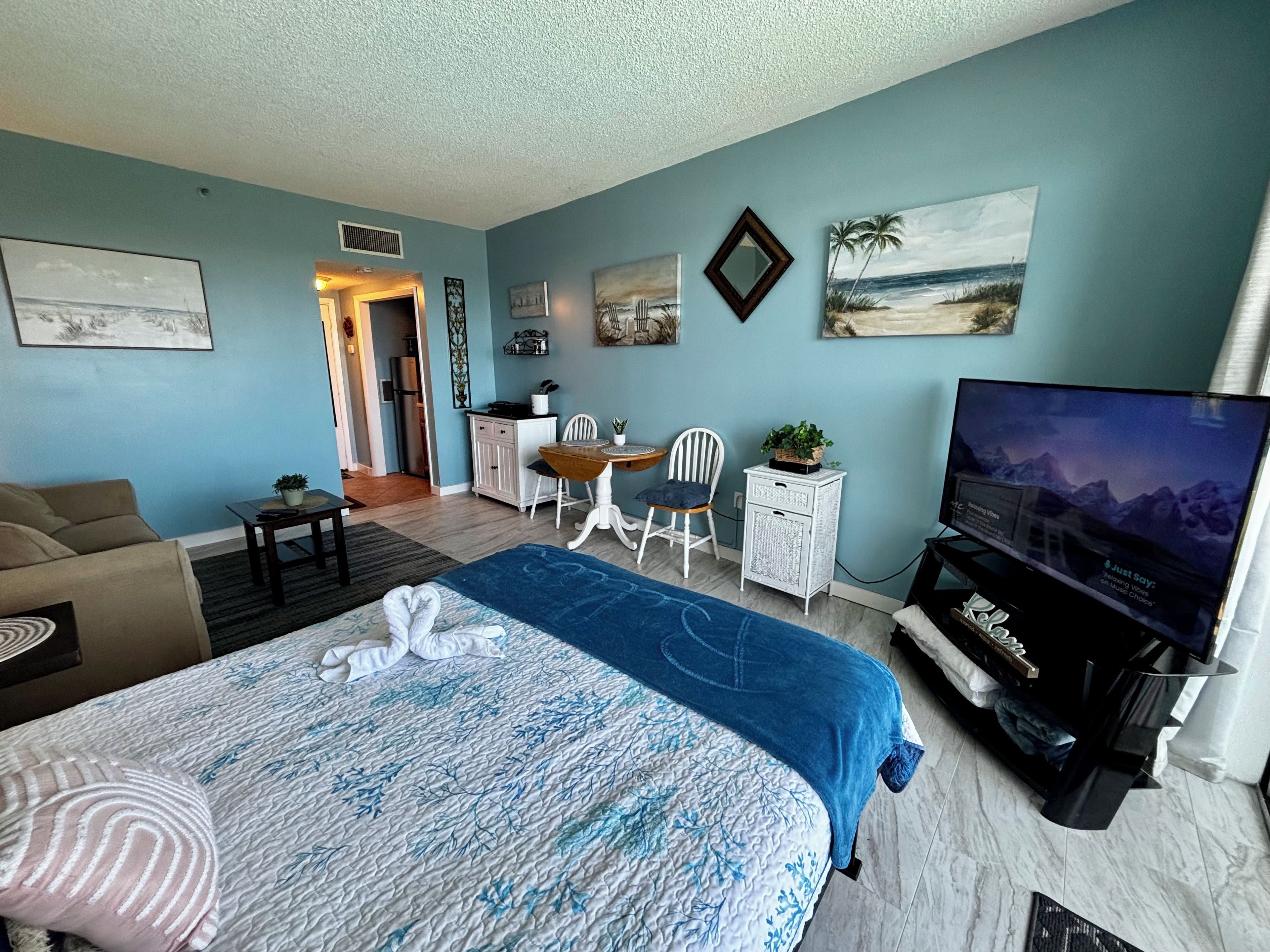 A hotel room with a bed, a TV, a desk, and a chair.