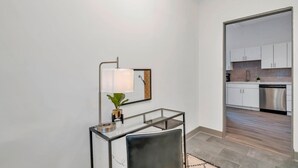Ein modernes Interieur mit Schreibtisch, Stuhl, Lampe und Blick in einen Küchenbereich.