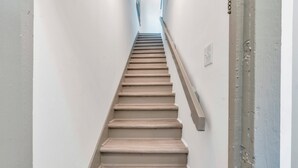 Eine Treppe mit Holzboden und Handlauf, die in einem schmalen Gang nach oben führt.