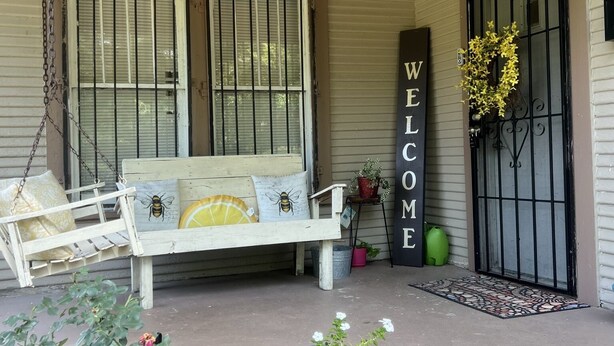 A porch with a white bench, a welcome sign, a lion statue, and a hanging light fixture. - The Lyons Den - Great work place with high speed internet near downtown.  (Jackson)