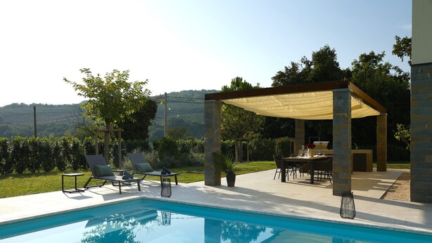 Ein Schwimmbecken mit Liegestühlen und einer überdachten Terrasse.