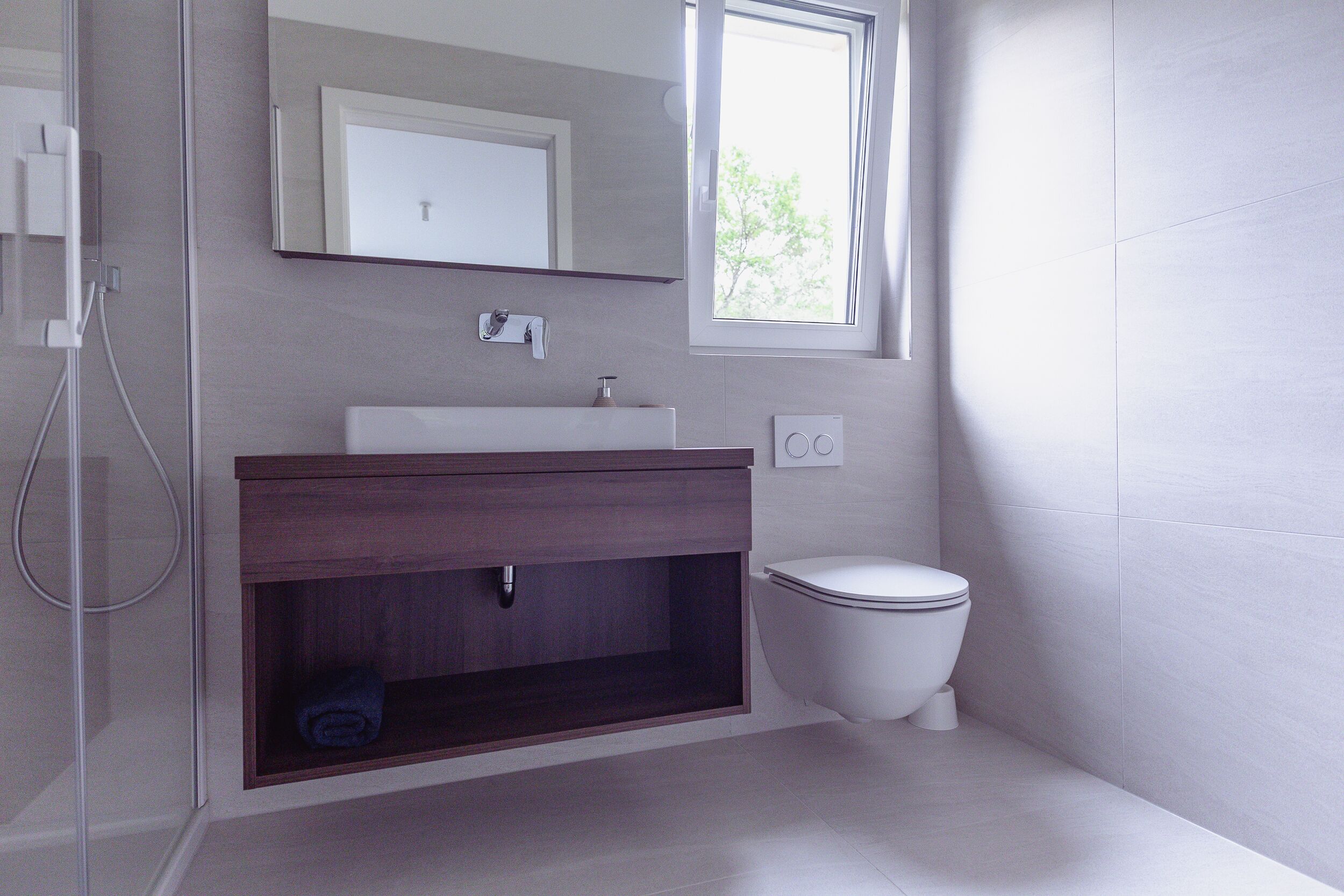 A modern bathroom with a shower, a sink, and a toilet.
