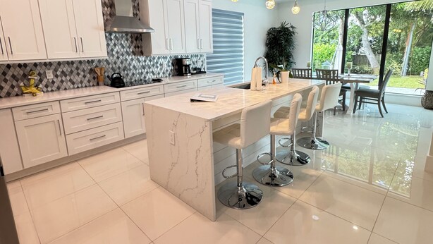 A modern kitchen with white cabinets, a marble island, and pendant lighting. - Tropical Oasis!! New Construction! In the Heart of Naples!! PET FRIENDLY! (Naples)