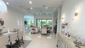 A spacious, modern living area with a dining set, a sofa, and a cabinet. - Tropical Oasis!! New Construction! In the Heart of Naples!! PET FRIENDLY! (Naples)
