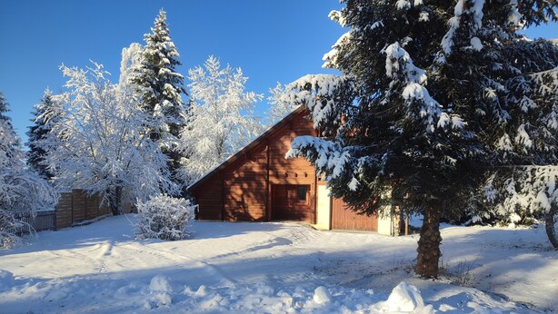 A wooden cabin with a snow-covered landscape, surrounded by trees. - Chalet au Coeur de la Nature (Cerniébaud)
