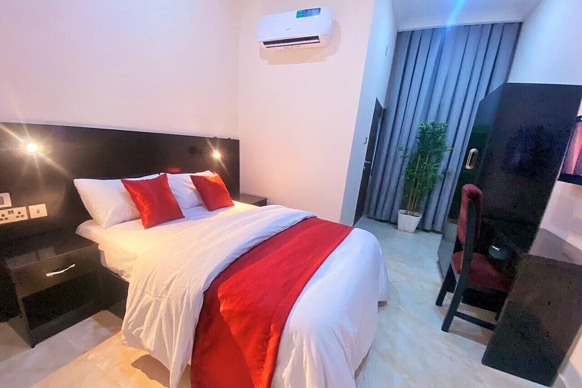 A modern hotel room with a large bed, a desk, and a chair.