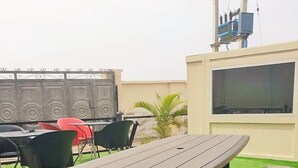 Une terrasse sur le toit, avec une table de pique-nique et des bancs, entourée de chaises et d’une clôture décorative.