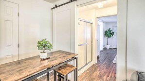 Un interior moderno con una mesa de comedor de madera, una planta en maceta y un puertas corredera que da a otra habitación.