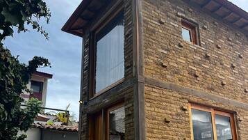 A two-story building with a stone facade, a wooden staircase, and a small window.