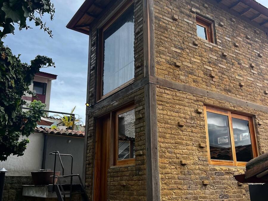 A two-story building with a stone facade, a wooden staircase, and a small window.