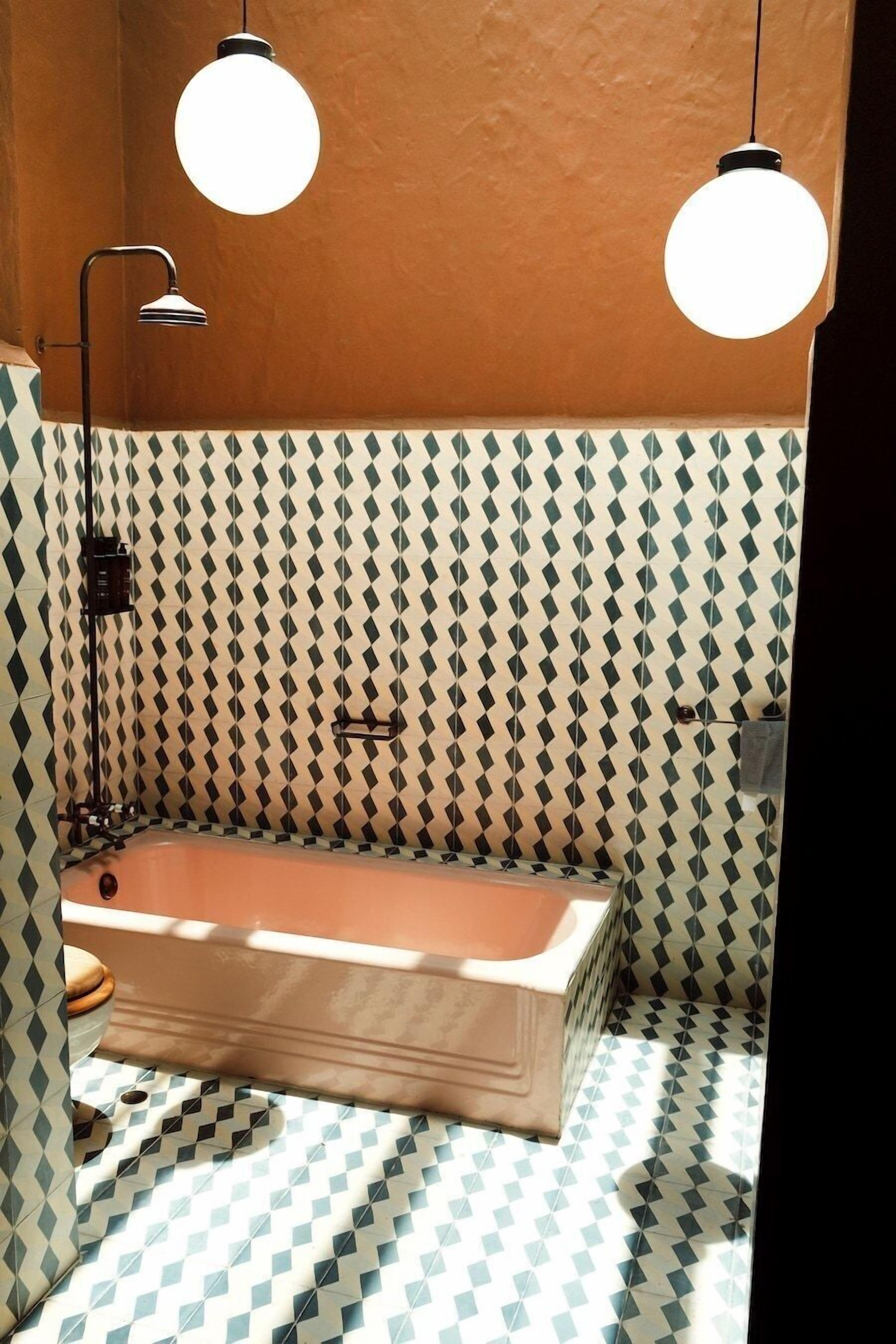 Un baño con una bañera, dos lámparas colgantes y paredes con diseño.