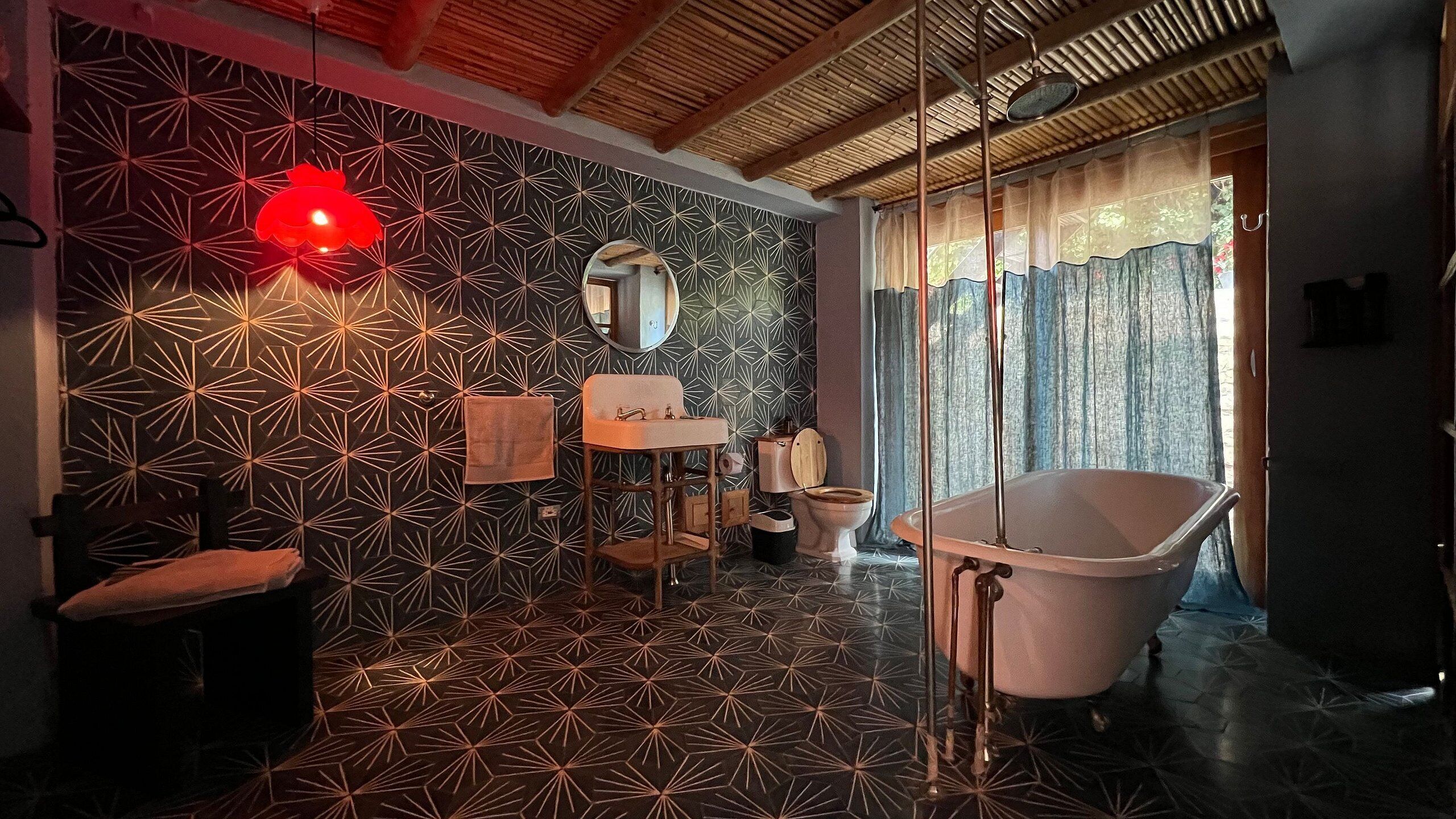 Ein Badezimmer mit Wand in geometrischem Muster, einer freistehenden Badewanne, einem Waschbecken und einer Toilette.