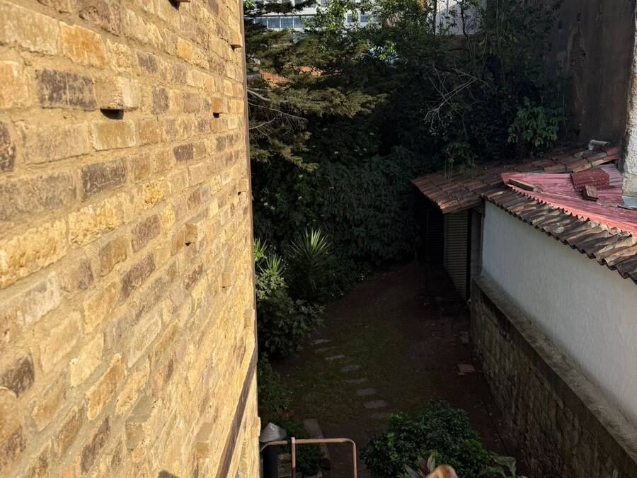 Ein Innenhof mit Backsteinmauer, einer Treppe und Kübelpflanzen.