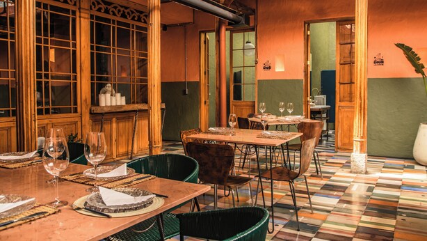 En restaurang med trämöbler, ett kaklat golv och en grön vägg.