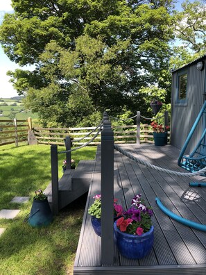 A wooden deck with rope swings, a rope ladder, and potted plants. - The Peacock Shepherds Hut at Hafoty Boeth (Corwen)