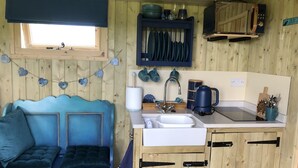 A cozy cabin-style room with a blue sofa, wooden cabinets, a sink, and a window.