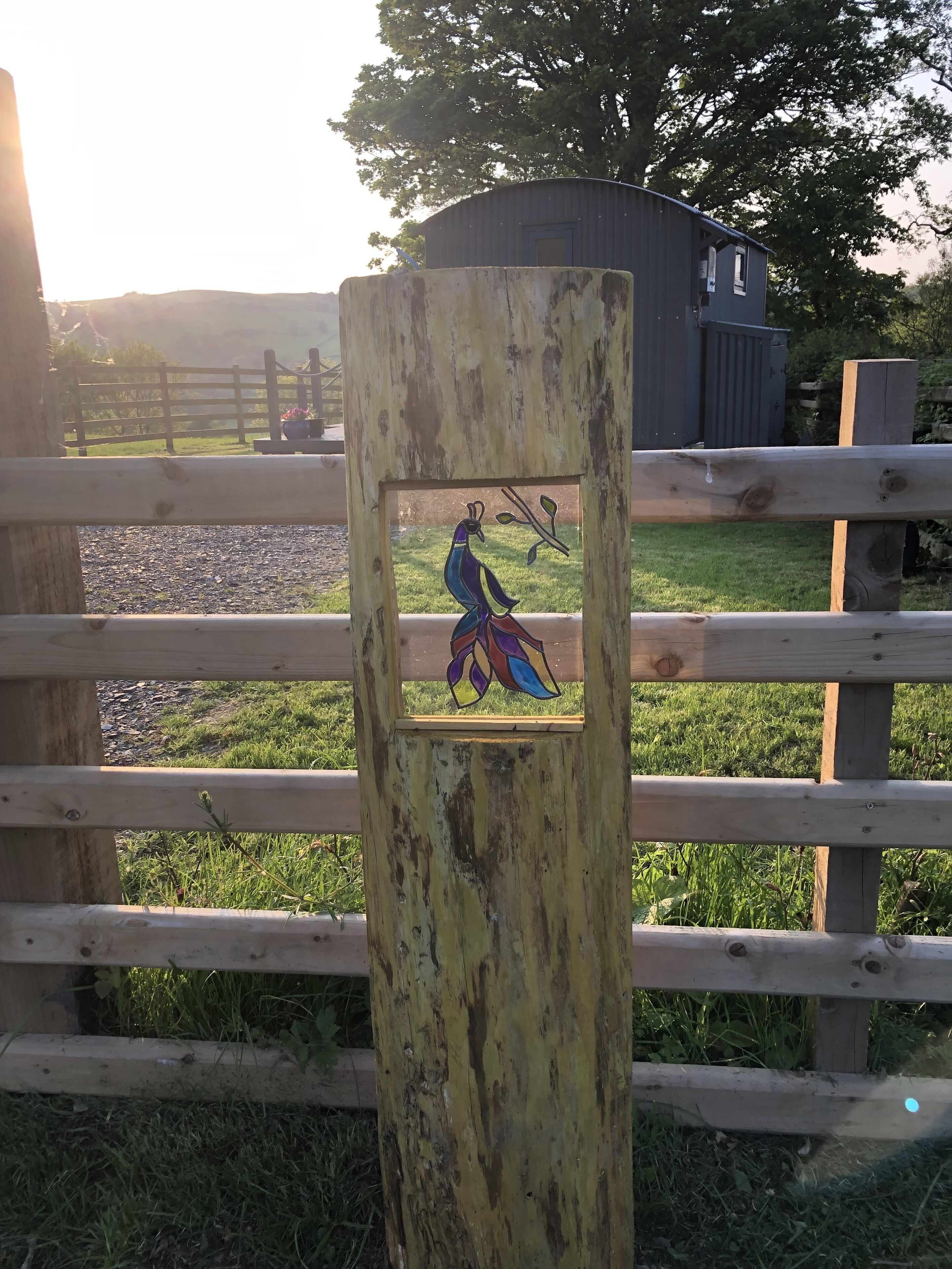 A rustic wooden fence with a decorative metal plaque featuring a peacock.