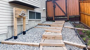 Eine Holzterrasse führt zu einem Haus mit einem Metalltor und einem Holzzaun.