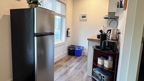 Eine kleine Küche mit einem Edelstahlkühlschrank, einer Kaffeemaschine und einem Toaster auf einer Holzausziehtafel.