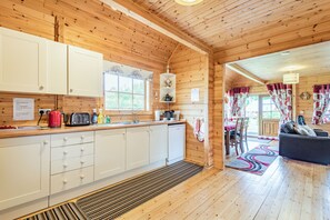 A wooden cabin interior with a kitchen, dining area, and a living room. - Robin Lodge (Llanbedr)