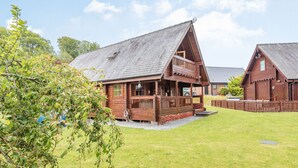 Une cabane en bois avec un porche, une terrasse couverte et une cour gazonnée.