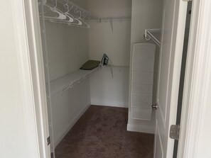 Comfortable closet with a towel rack, shelf, and mirror.