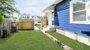 A residential backyard with a wooden fence, a concrete staircase leading to a house with blue siding, and a white van parked in the background. - Iconic Speedway Location next to Indy 500 track, amenities, and restaurants (Indianapolis)