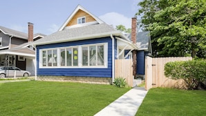 A single-story house with a blue exterior, a front porch, and a wooden fence. - Iconic Speedway Location next to Indy 500 track, amenities, and restaurants (Indianapolis)