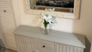 Un dormitorio con cama, mesita de noche, espejo y cómoda con cajones.