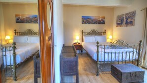 Une chambre d’hôtel avec deux lits, des meubles en bois et des tableaux aux murs.