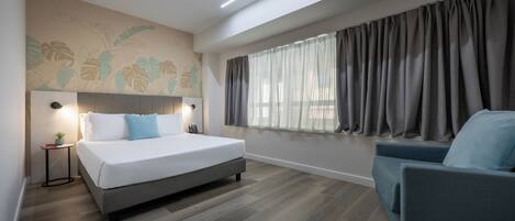 A modern bedroom with a large bed, a bedside table, a chair, a window with curtains, and a wall mural.