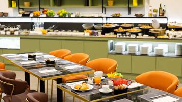 Un buffet de petit-déjeuner proposant une variété d’aliments et un espace repas avec des tables et des chaises.