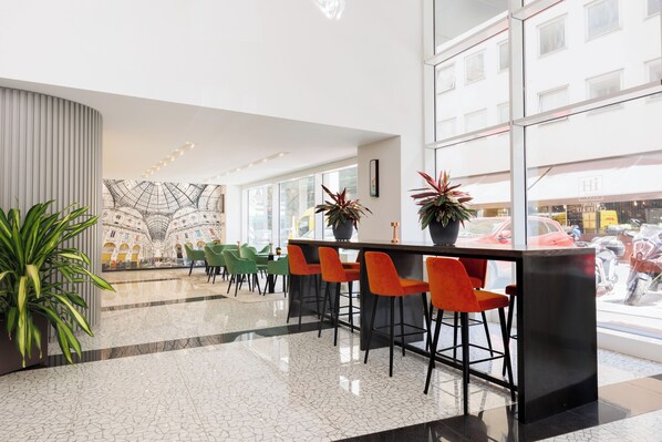 A modern lobby with a bar area, green and orange chairs, and large windows. - IH Hotels Milano Centrale (Milan)