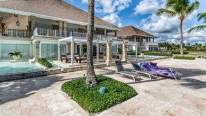 Een resort met een zwembad, ligbedden en een overdekt gedeelte met uitzicht op de oceaan.
