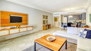 Uma sala de estar moderna com uma televisão de tela plana fixada em um painel de madeira, um sofá e uma mesa de centro.