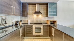 Cozinha moderna com armários de madeira escura, coifa de aço inoxidável e backsplash revestido de azulejos.