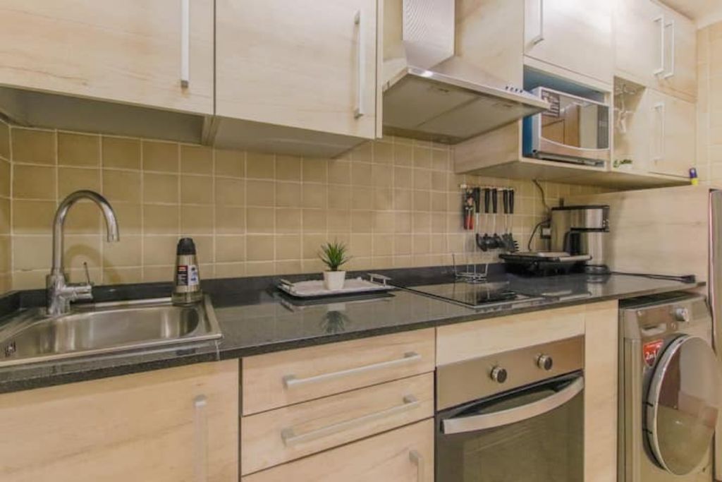 A kitchen with a sink, stove, microwave, and oven.