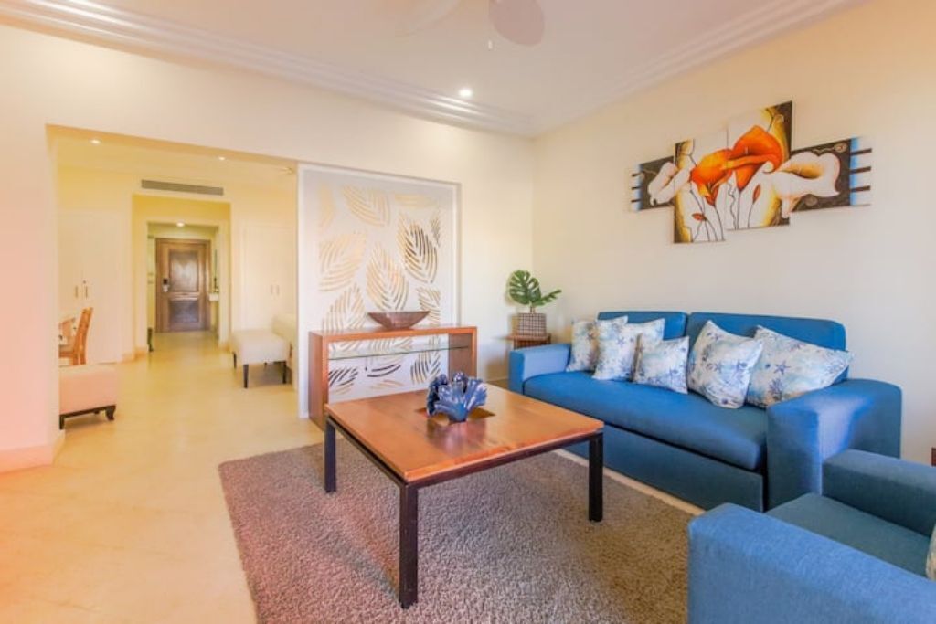 A living room with a blue sofa, a coffee table, and a decorative wall piece.