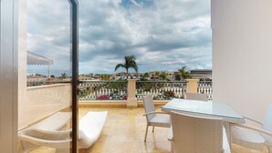 A balcony with a table and chairs, a view of the cityscape, and a cloudy sky. - Marina Oasis Retreat at Fishing Lodge, Cap Cana (Punta Cana)
