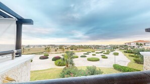 A landscaped garden with neatly trimmed bushes and a palm tree, viewed from a balcony. - 2BDR Cap Cana Retreat @ GBL (Punta Cana)
