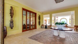 A spacious lobby with a tiled floor, a large wooden bench, and a planter with greenery. - 2BDR Cap Cana Retreat @ GBL (Punta Cana)
