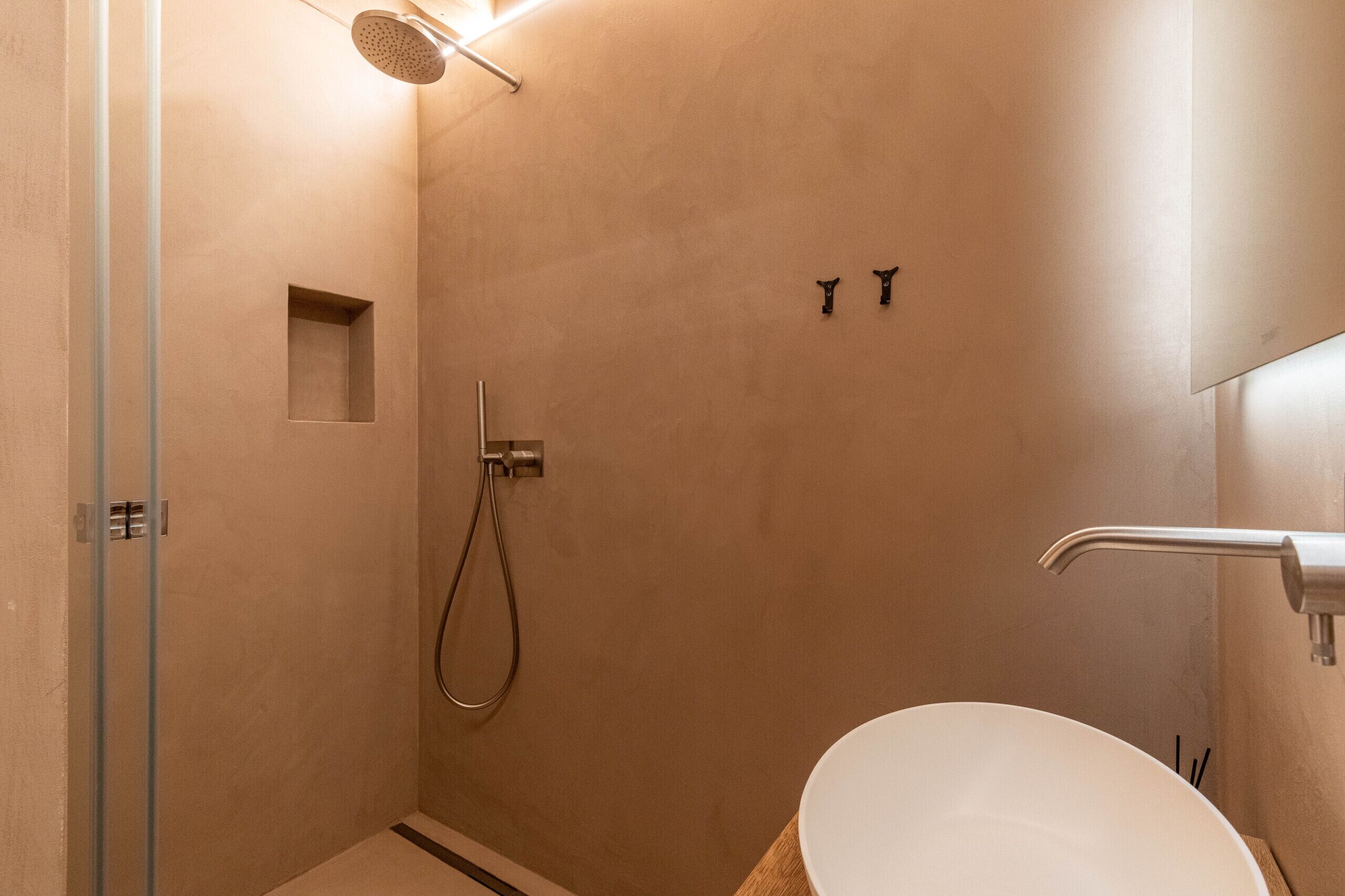 A modern bathroom with a glass shower enclosure, a white sink, and a wall-mounted towel rack.