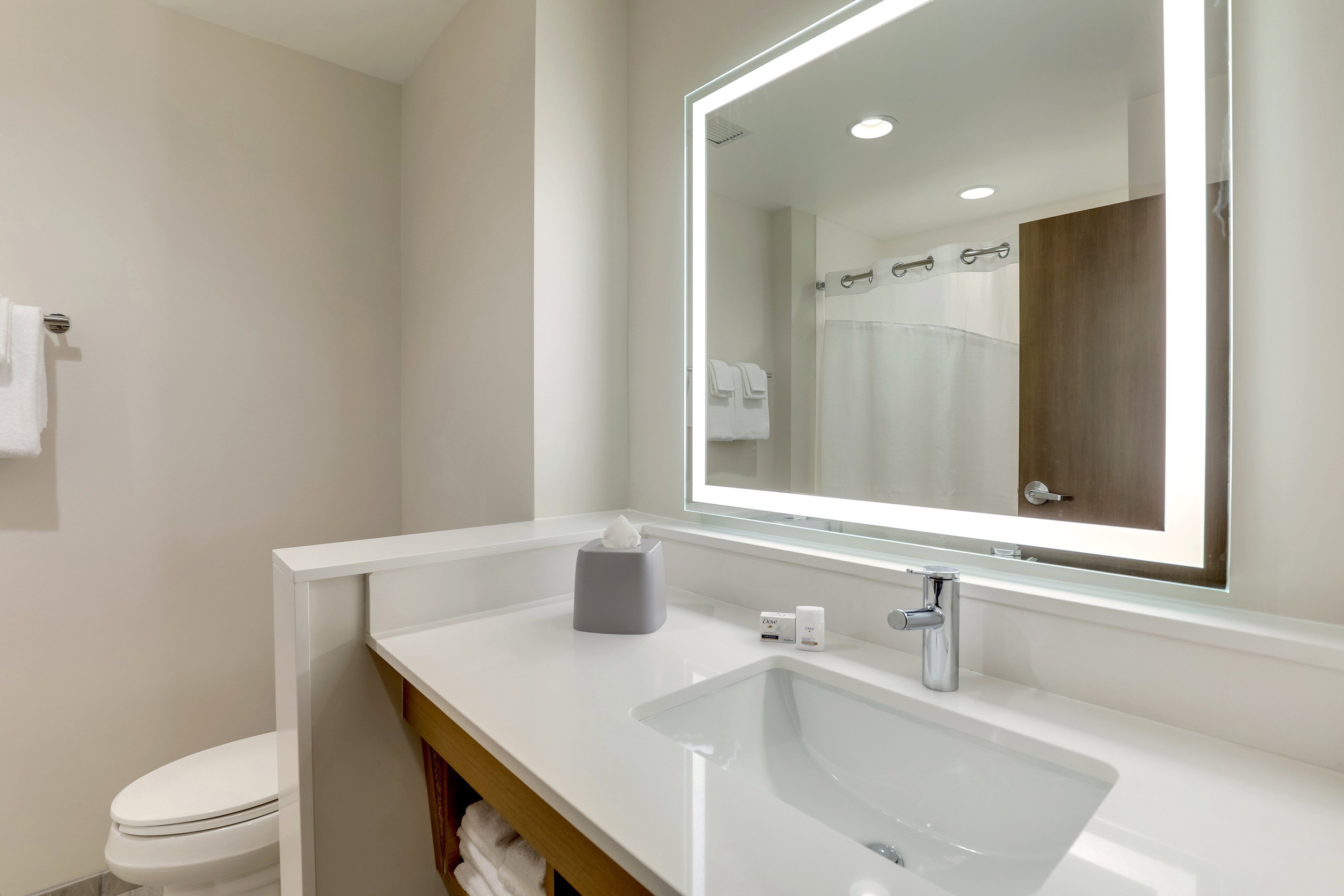 A modern bathroom with a white sink, a large mirror, and a toilet.