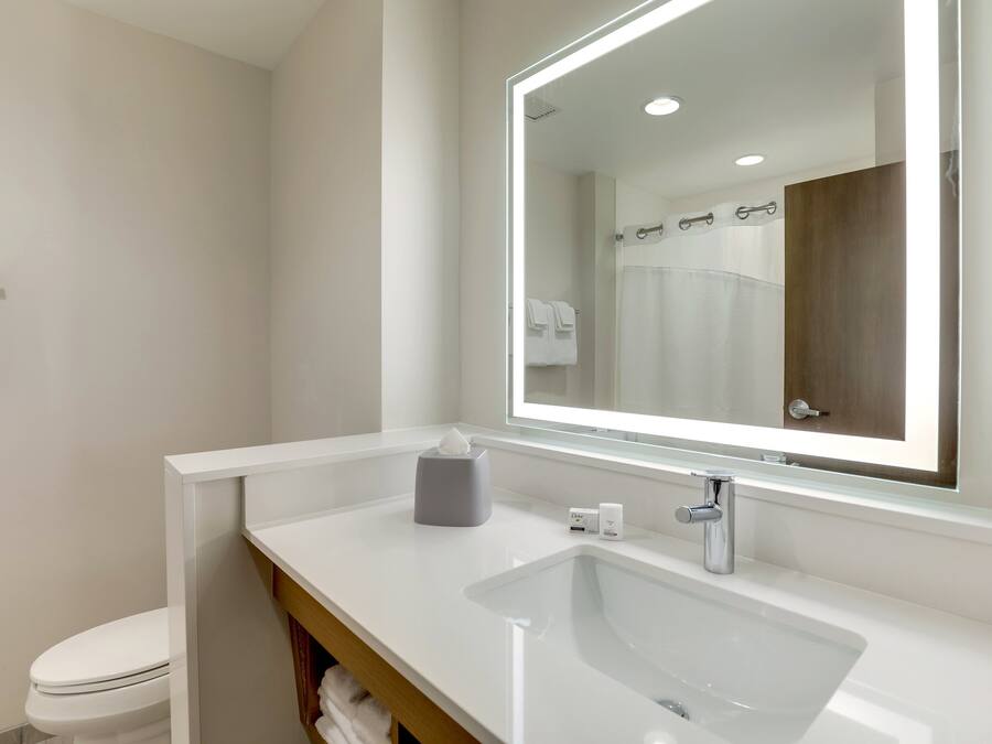 A modern bathroom with a white sink, a large mirror, and a toilet.