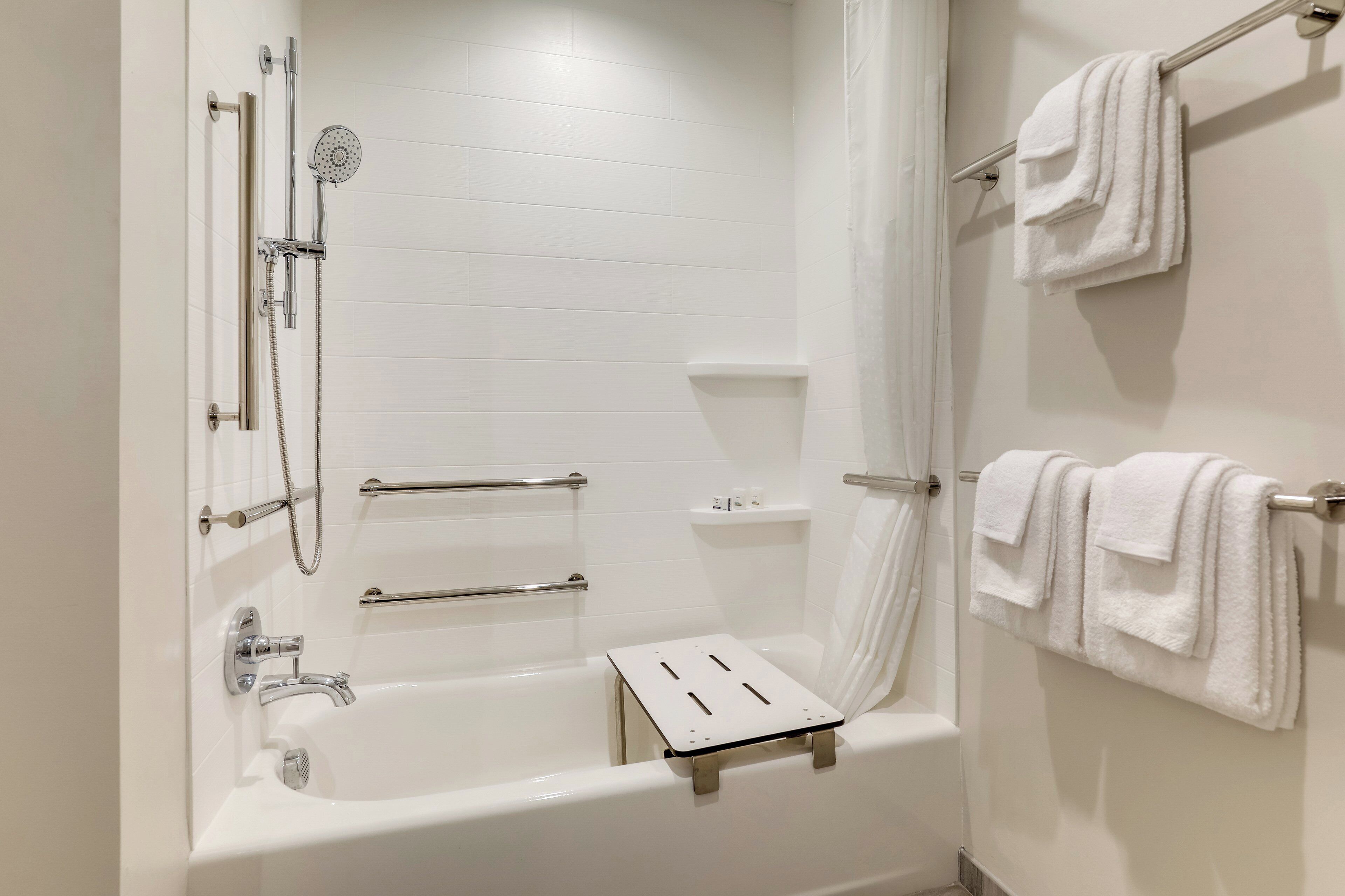 A modern bathroom with a bathtub, shower, and towel rack.