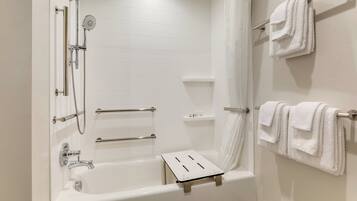 A modern bathroom with a bathtub, shower, and towel rack.