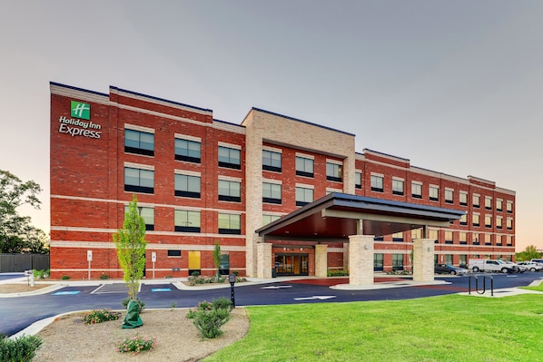 A Holiday Inn Express building with a brick facade, a covered entrance, and a parking lot.