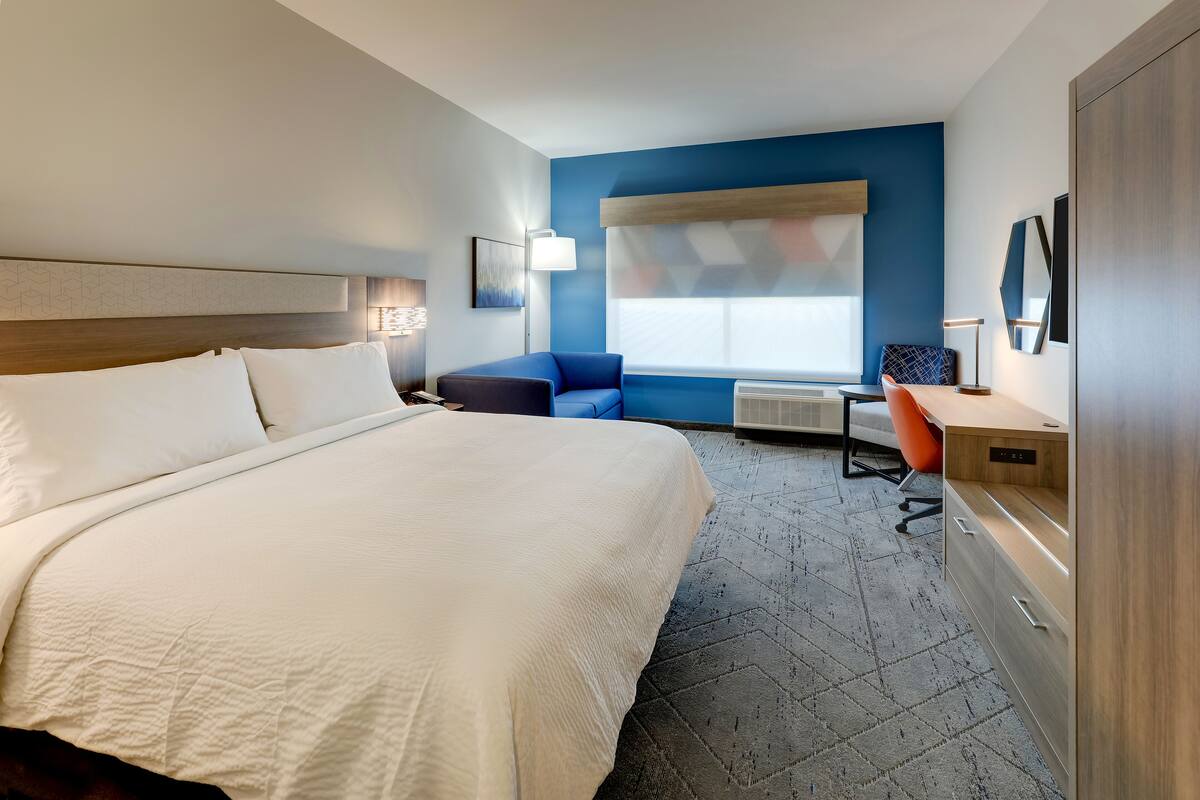 A hotel room with a large bed, a desk, a chair, and a window with a view.