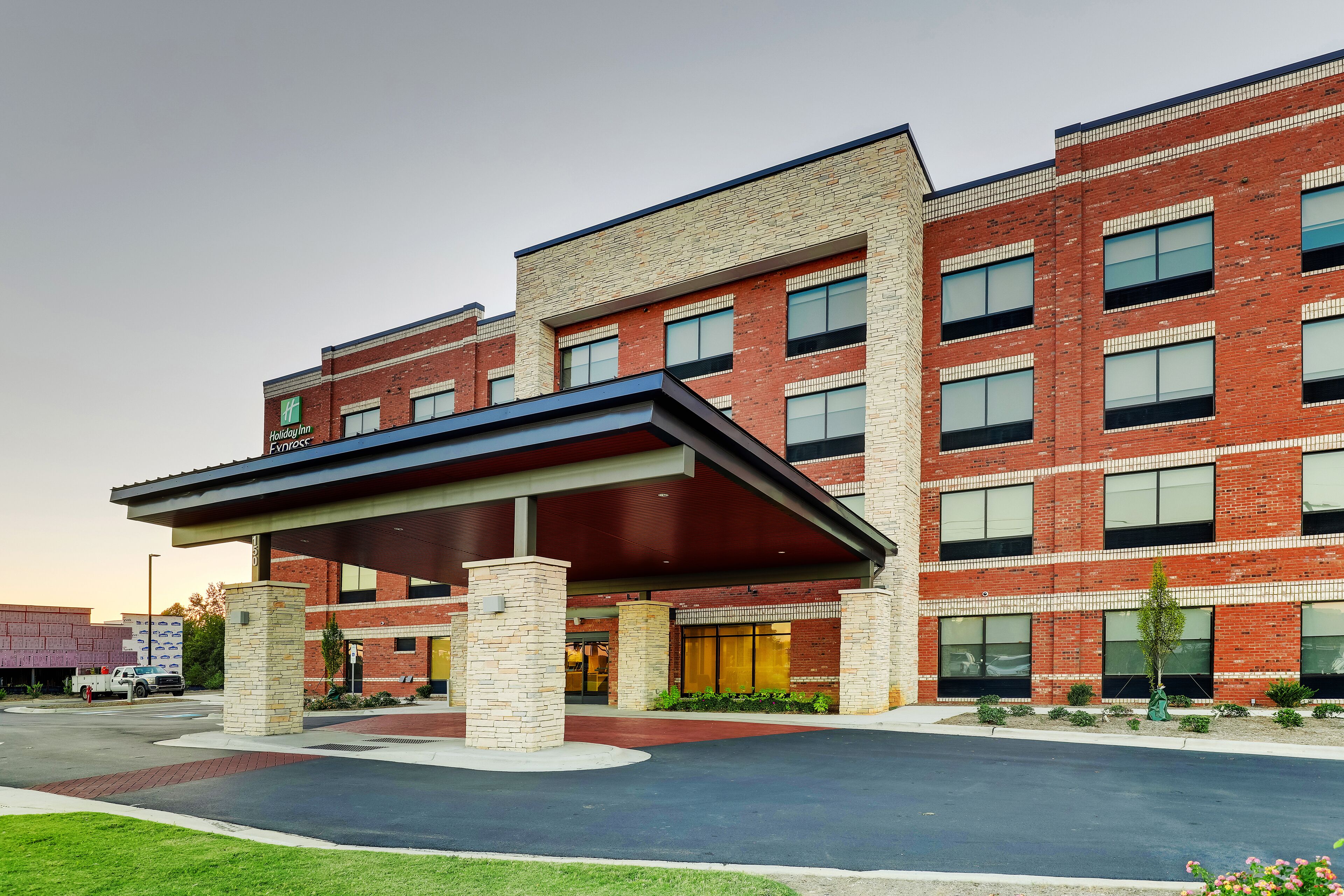 A modern hotel with a brick facade, a covered entrance, and a landscaped driveway.